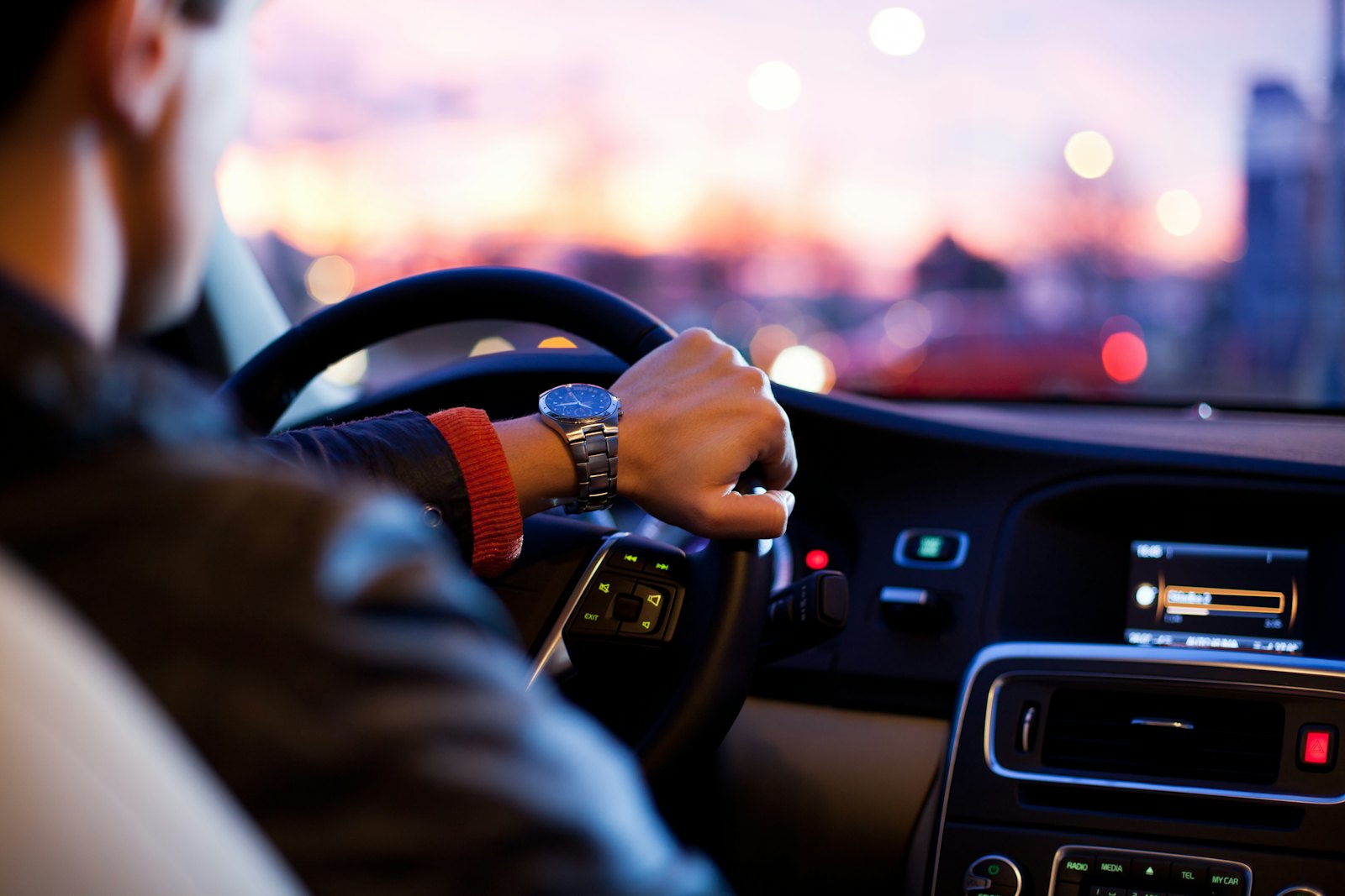A driver's hand on the steering wheel of a modern car